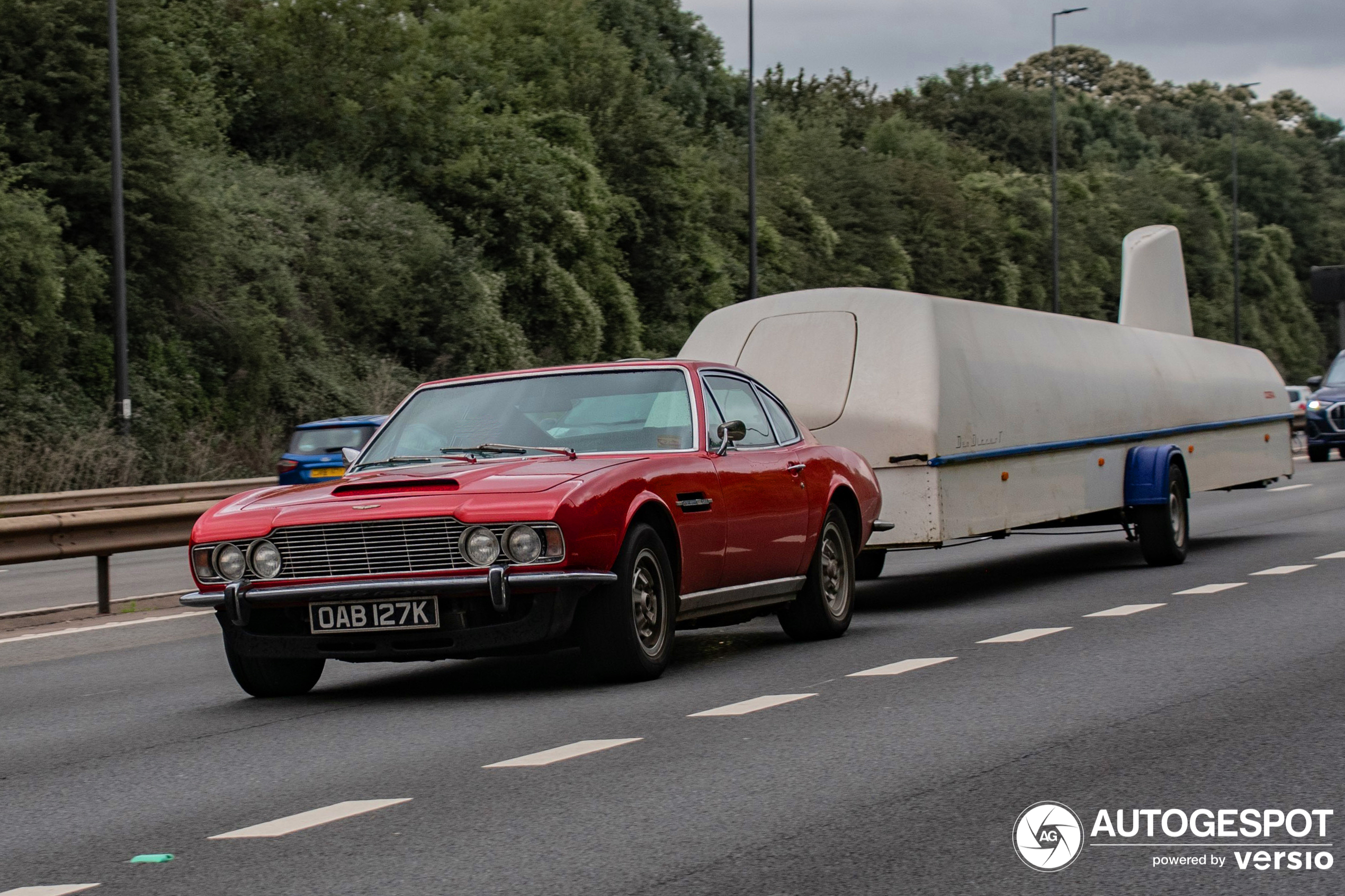 An old DBS with a trailer drives on the highway