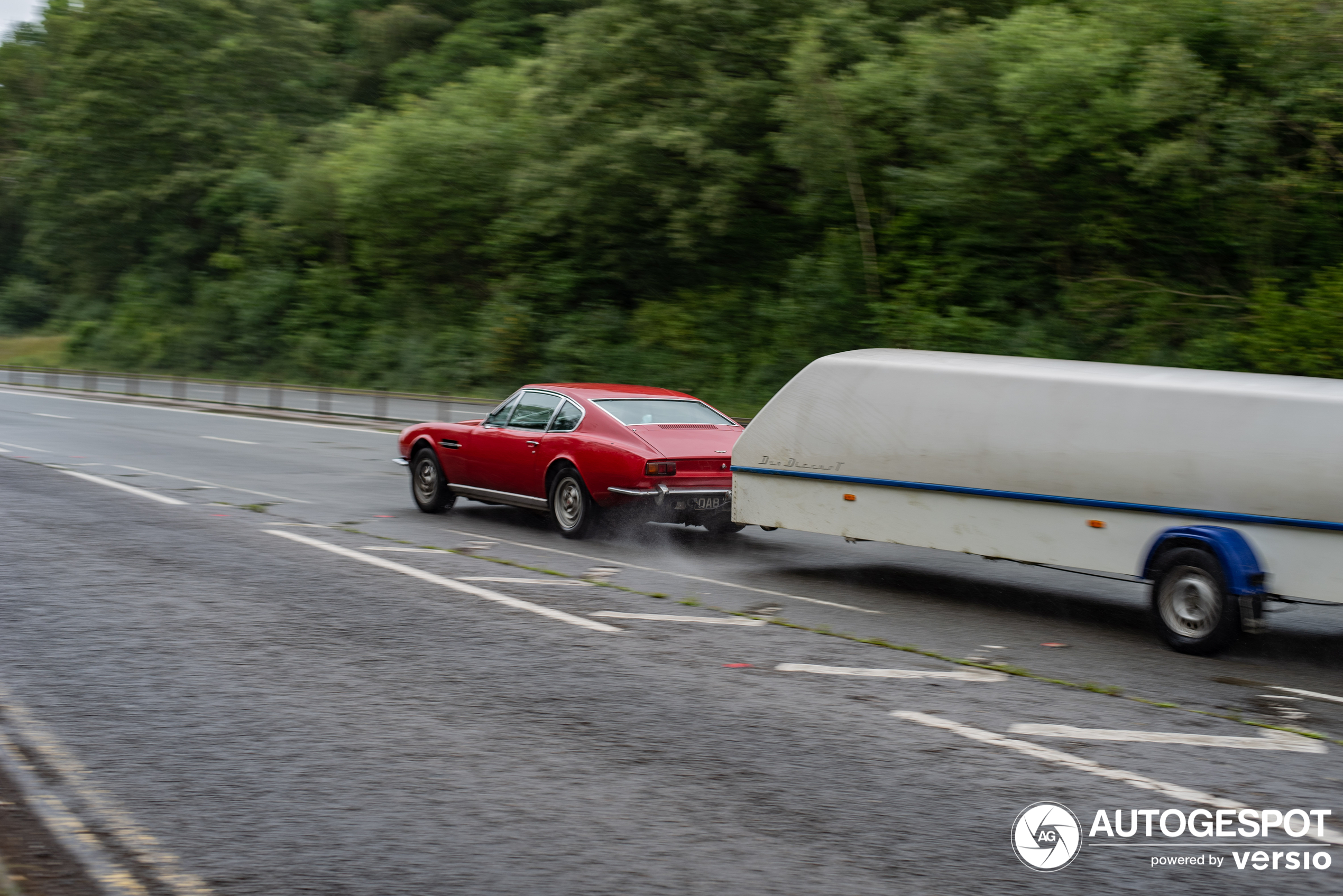 An old DBS with a trailer drives on the highway